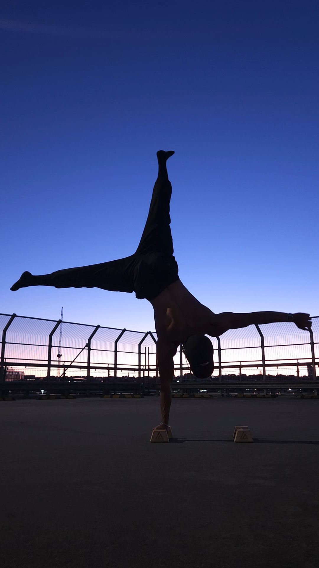 Felix Ng performing a one-arm handstand at night